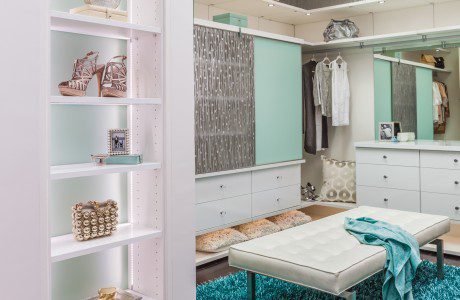 White Themed Walk in Closet with Cabinets Lighted Shelving and Vanity Turquoise and Etched Glass Accent Doors and Stand Alone Bench Seating