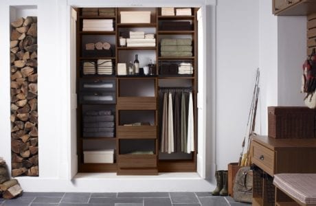 Linen cabinet storage with shelves, cubbies, and hanging rods in a dark wood grain finish by California Closets