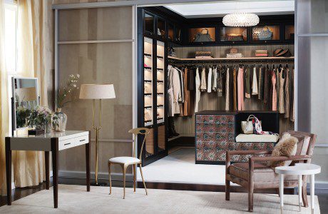 LIght Brown Walk in Closet with Dark Brown Fronting Closet Rods Shelves and Lighted Display Cabinets