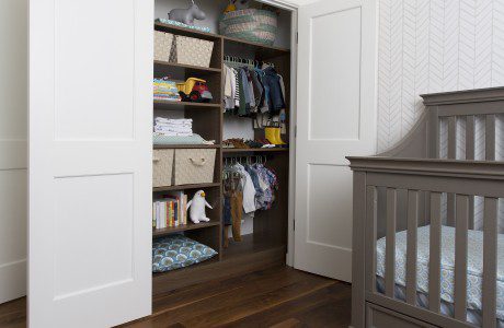 Dark brown reach-in closet for nursery and kids room with adjustable shelving, hanging space, and overhead storage