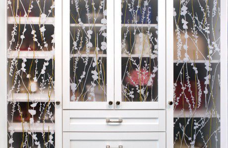 Close up of White Shaker Cabinet with Drawers and Glass Decoratively Etched Doors and