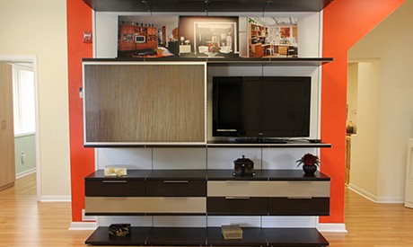 Black Entertainment Center with Floating Shelves and Cabinets White Backing and Light Brown Accent Drawers and Siding Door