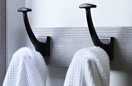 Black towel and coat hangers with light gray backing board by California Closets