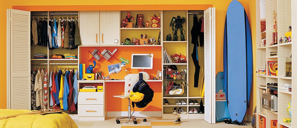 White Children's Closet With Shelving Closet Rods Cabinets Built in Desk and Yellow and Orange Backing