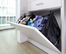 White closet cabinet with fold out black storage baskets for laundry by California Closets