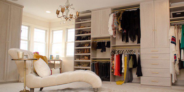 Mottled White Walk in Closet with Lounge Chair Shelving Cabinets and Gold Accented Closet Rods and Handles