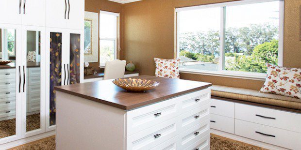 White Walk in Closet with Mirrored Wardrobe Doors Built in Bench Seating and Stand Alone Dresser with Dark Brown Top