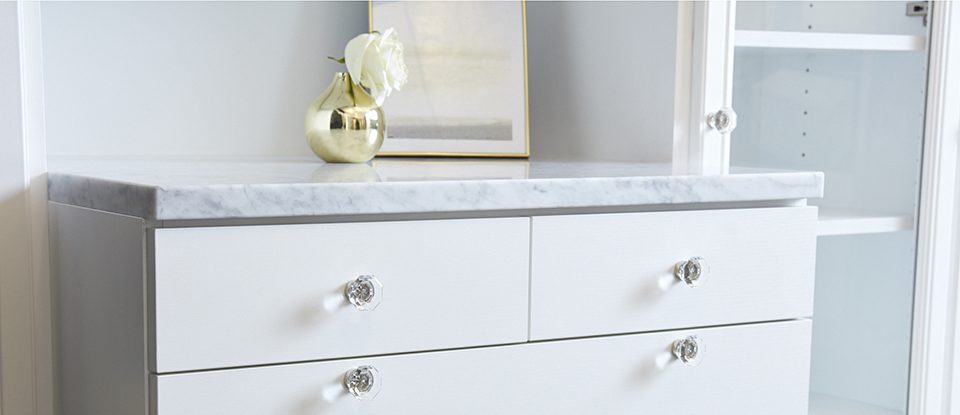 Close Up of White Dresser With Clear Handles and Granite Counter Top