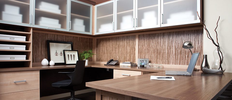 Light Wood Office with Textured Wood Backing Cabinets with Frosted Glass Doors and White Trim and a Built in Wrap Around Desk