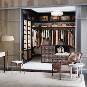 LIght Brown Walk in Closet with Dark Brown Fronting Closet Rods Shelves and Lighted Display Cabinets