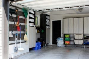 Client Stories Redesigned Garage Storage Space with Dark Brown Hanging Rack and Shelving and Light Wood Cabinets