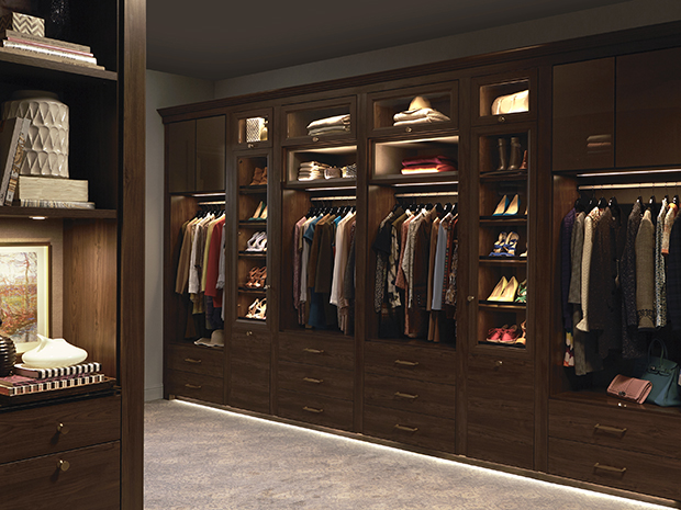 Walk in Closet with Dark Wood Cabinets Shoe Racks Closet Rods and Built in Lighting