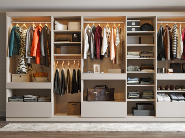Organización de armarios de pared con estantes abiertos, cajones personalizados y postes para colgar prendas de California Closets