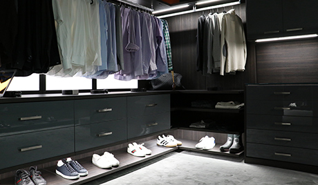 Black Walk in Closet with High Gloss Cabinets and Drawers Built in Lighting and Wood Grain Backing