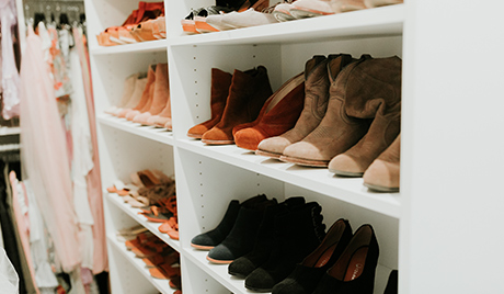 Shoes organized by color held in white shelves