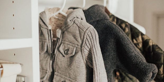 Baby clothes hanging in white reach in closet