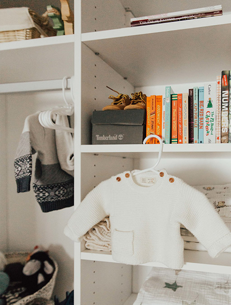 A baby shirt hanging on display amongst white shelving with various organized items