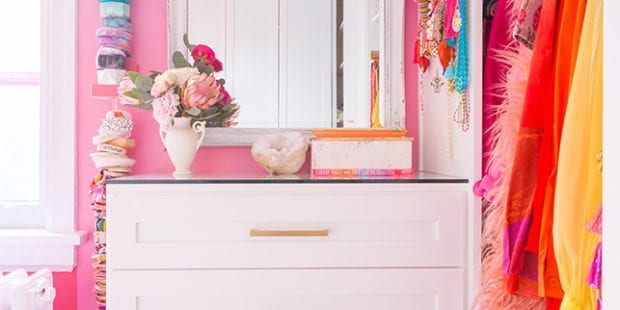 A white dresser surrounded by colorful hanging clothes and accessories