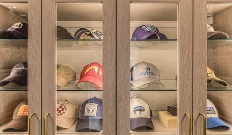 Cabinets with clear glass fronts housing baseball caps