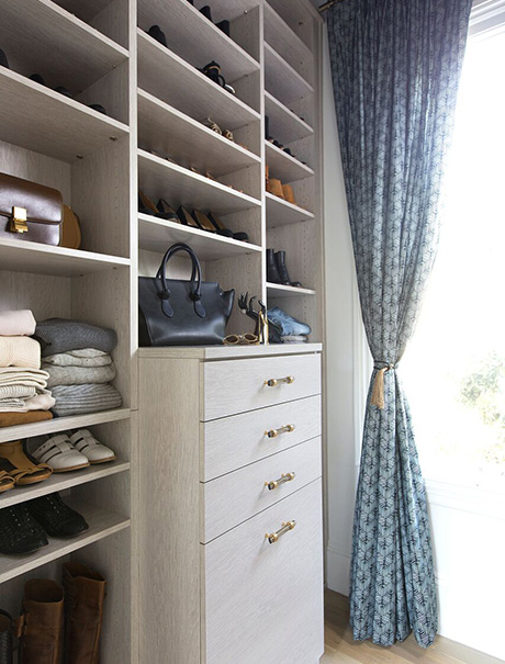 Drawers with gold hardware surrounded by shelving in front of a large window
