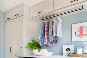 Light tan laundry room cabinetry with hanging pole to dry clothes