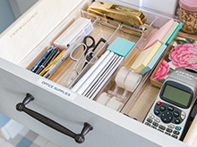 Office supplies organized in a drawer with clear containers