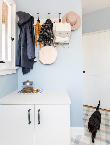 Accessories hanging on coat hooks above a custom white cabinet