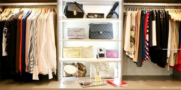 Organized clothes hanging and purses displayed in white shelving with LED lights