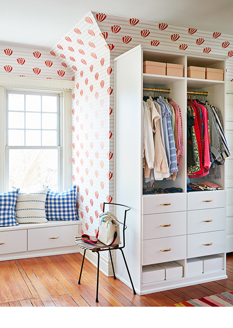 Clare Vivier's luxury walk in closet with colorful accents, a window bench and built in wardrobe created by California Closets