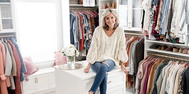 Fashion blogger Brittany Sjogren sitting on white island in her remodeled walk in closet