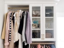 Hanging clothing space and glass cabinet doors in fashion blogger Brittany Sjogren's walk in closet by California Closets