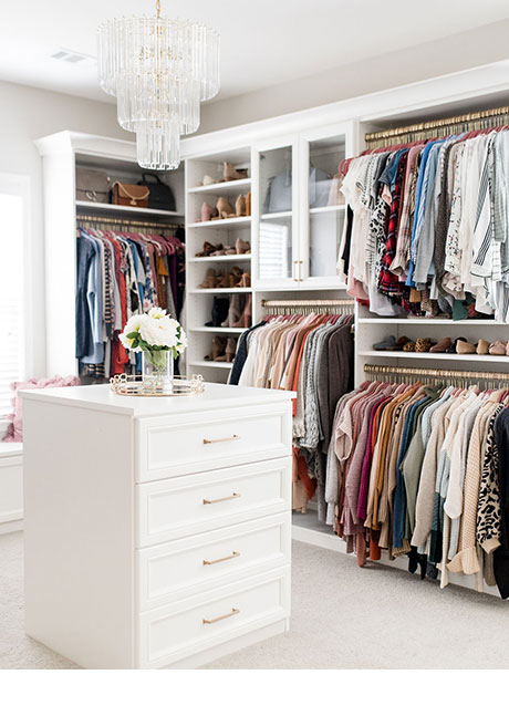 Closet with hanging space, room for shoes and a dresser with cabinets in the middle of the room