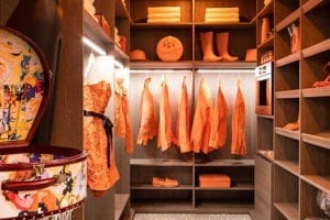 Walk in closet with wood finish and orange clothing and accessories hanging