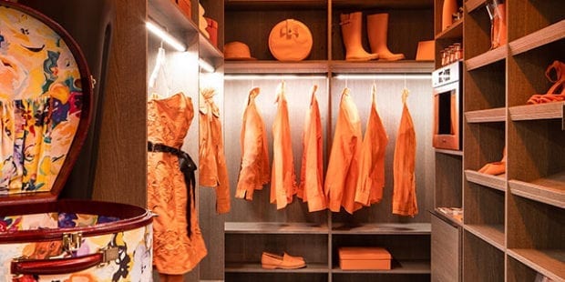 Walk in closet with wood finish and orange clothing and accessories hanging