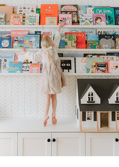 Daughter of photographer Syndey Gerten reaching for book in her new custom playroom storage