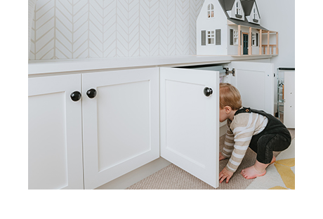 Son of photographer Syndey Gerten peaking inside cabinet of new custom playroom cabinet