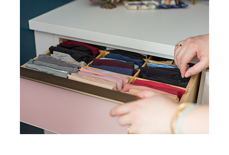 Image of hand reaching into pink drawer of neatly organized clothing