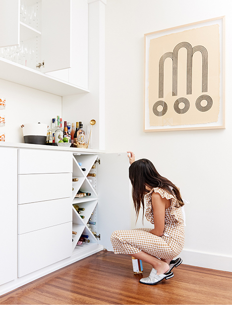 Magazine Editor Angela Tafoya peeking inside her custom dining room cabinets