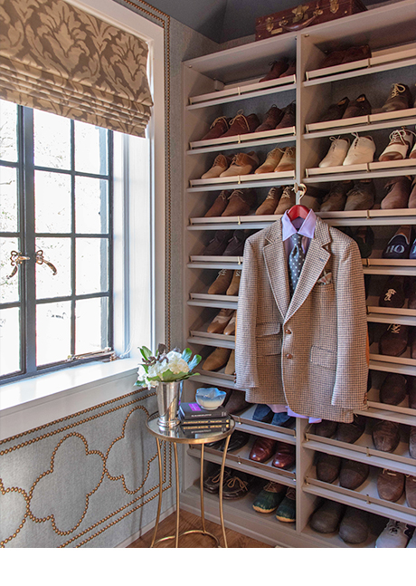 Shelving for dress shoes with coat hanging inside walk-in closet designed by Amber Colo and Sarah Smith