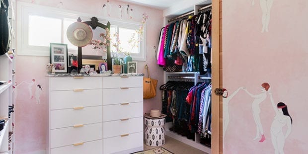 Pink walk in closet with white dresser with metal handles