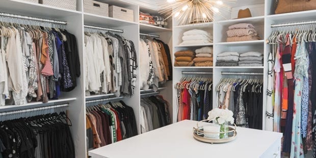 White custom walk-in closet with white island and overhead lighting