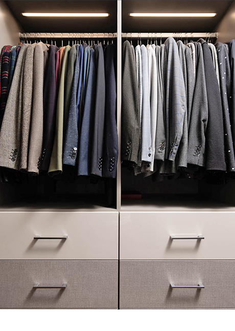 Suit jackets displayed from hanging rods and custom cabinetry for Brad Goreski