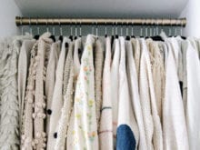 All white sweaters hanging in custom closet | California Closets