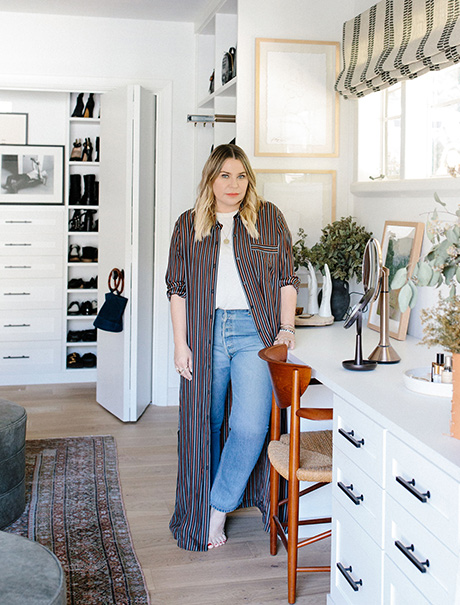 Designer Emily Current in her new custom walk in closet with a built in desk and drawers and shoe storage created by California Closets