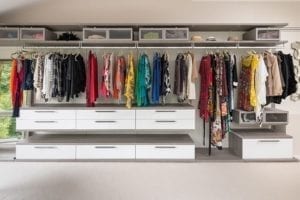 Boutique style master closet with white floating shelves and handing rods | California Closets