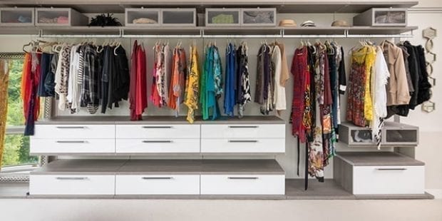 Boutique style master closet with white floating shelves and handing rods | California Closets