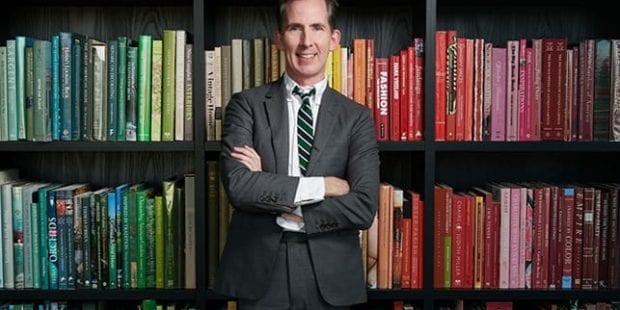 Kevin Sharkey standing in front of his rainbow colored book shelves | California Closets