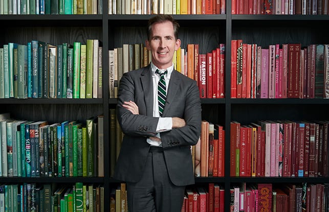 Kevin Sharkey standing in front of his rainbow colored book shelves | California Closets