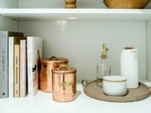 Organized pantry shelf with books, copper canisters and white vases