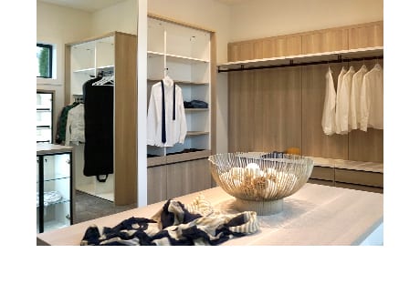 Cream colored island in walk-in closet with clear bowl